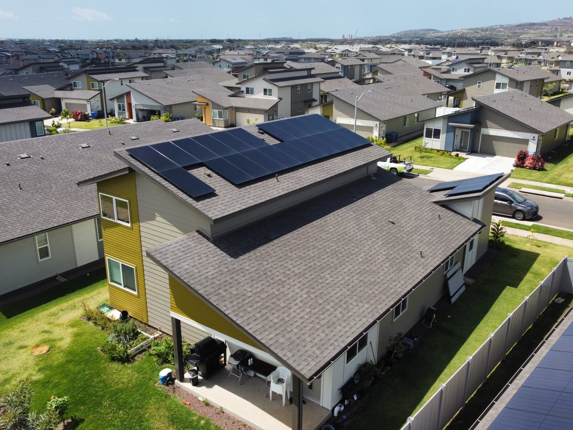 Modern Oahu home with rooftop solar panels and the Waianae mountains in the distance